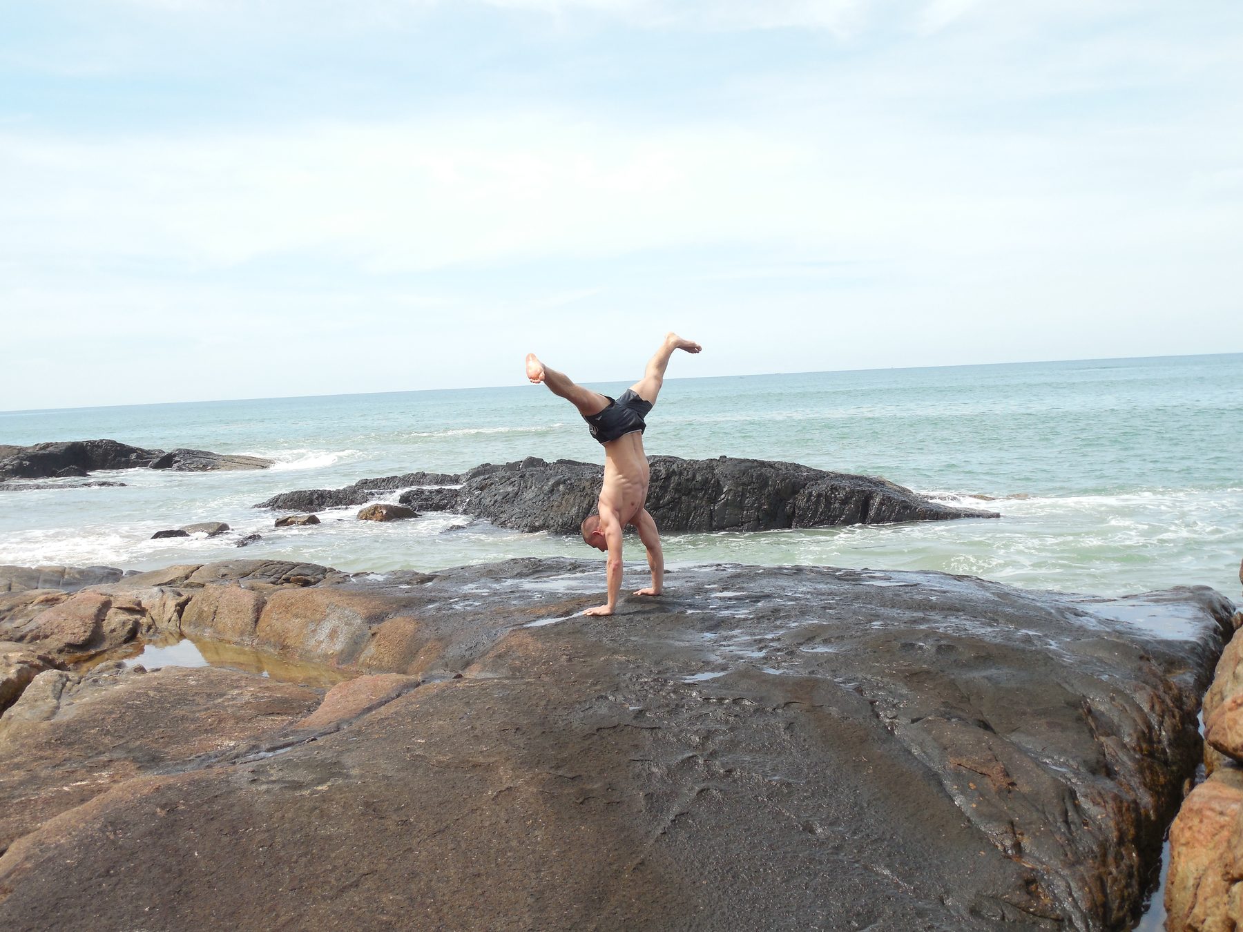 Daniel im Handstand auf einem Felsen am Meer