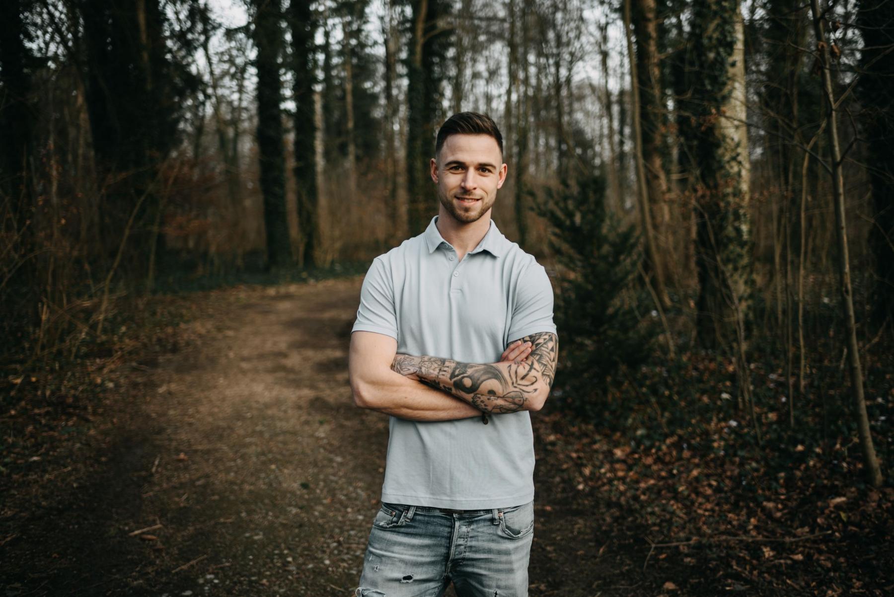 Daniel steht mit verschränkten Armen auf einem Waldweg
